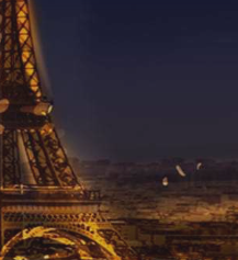 A nighttime photograph of the Eiffel Tower illuminated in warm golden light against a dark blue sky and cityscape.